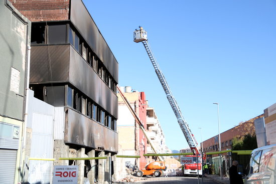 Firefighters supervise the demolition of the burned Badalona warehouse being carried out by contractors (by Mar Martí)